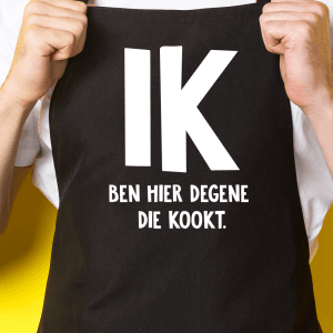 Zwart keukenschort met de tekst "Ik ben degene die kookt"